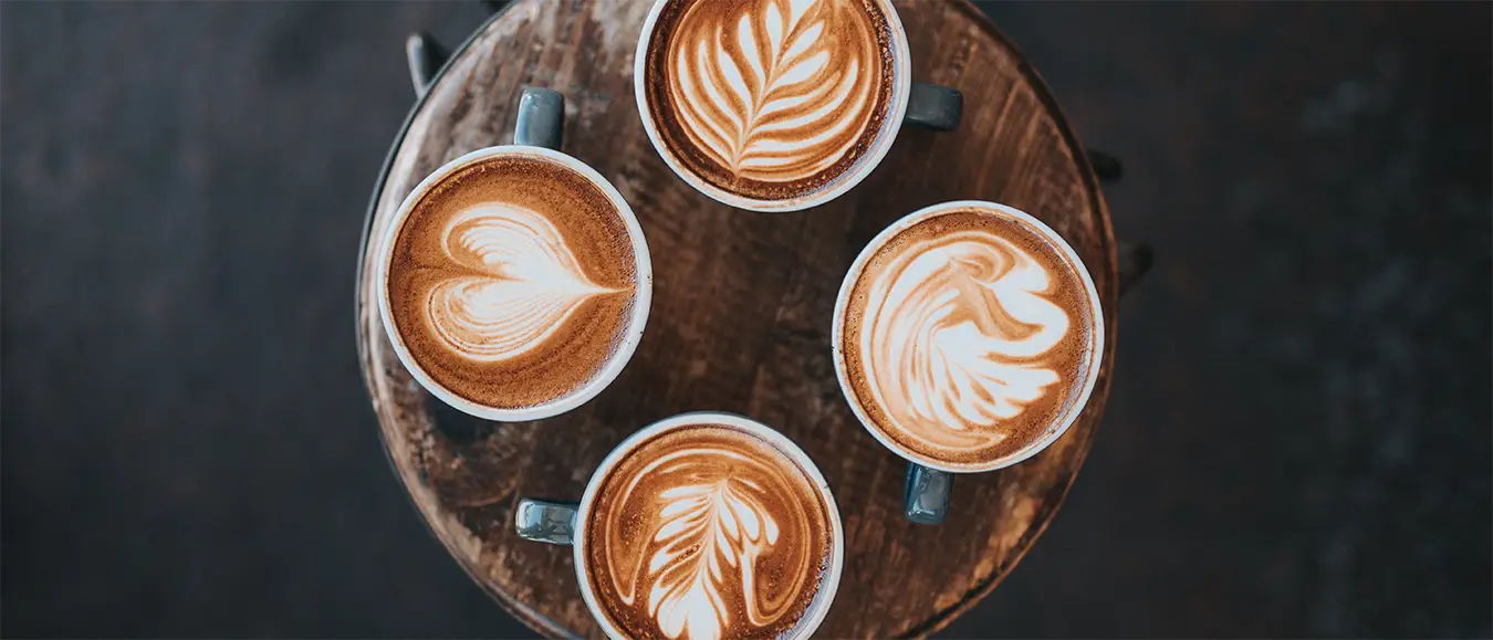 Verschiedene Latte Art Muster auf vier Cappuccino Tassen der Kaffeerösterei Martermühle