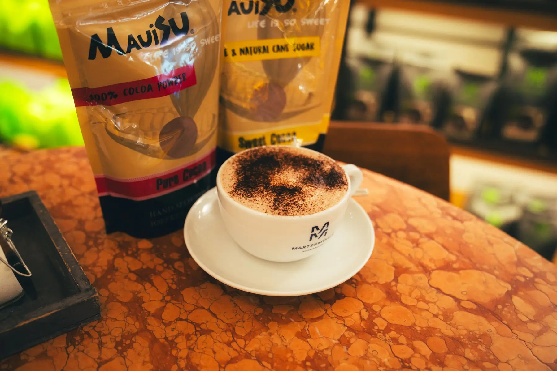 Zwei Packungen Kakao und eine Tasse heiße Schokolade im Kaffee Shop der Kaffeerösterei Martermühle