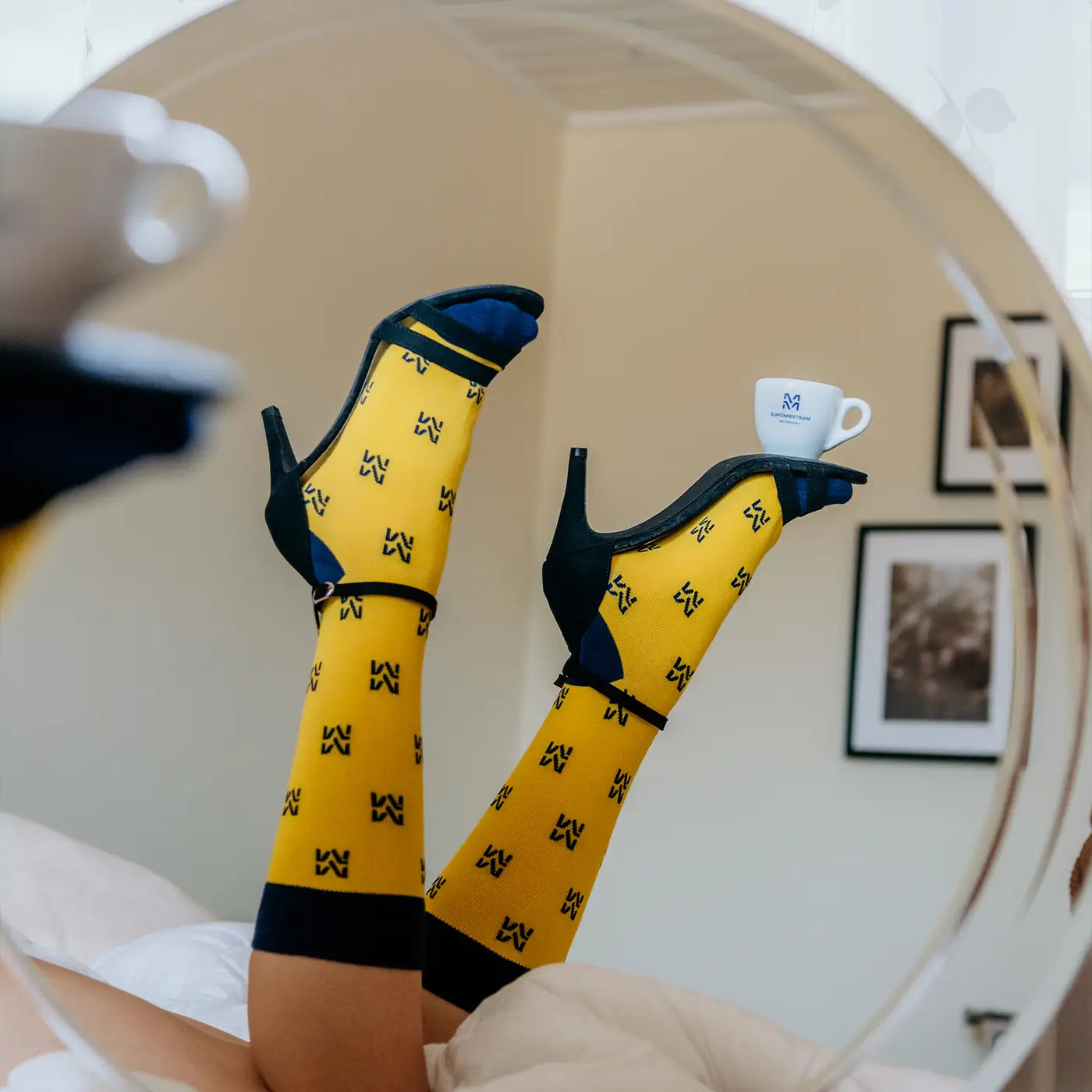 Ein Bildausschnitt von den Füßen einer Frau mit hohen Martermühle Socken und Stilettos auf denen eine Espressotasse balanciert wird