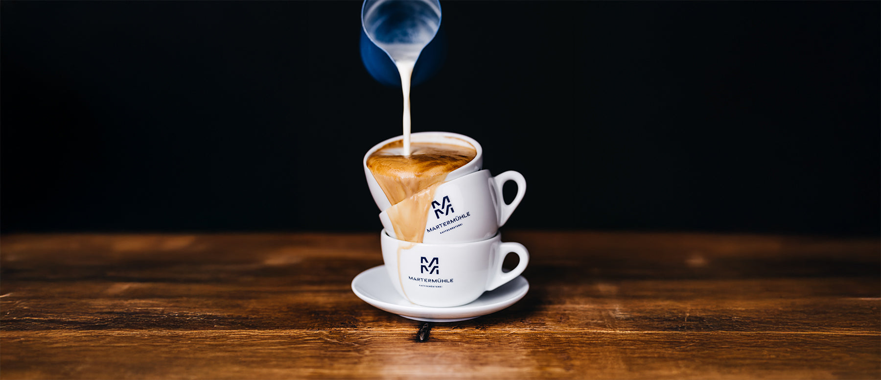 Drei Cappuccinotassen übereinander gestapelt mit Milchschaum, der den Kaffee zum überlaufen bringt.