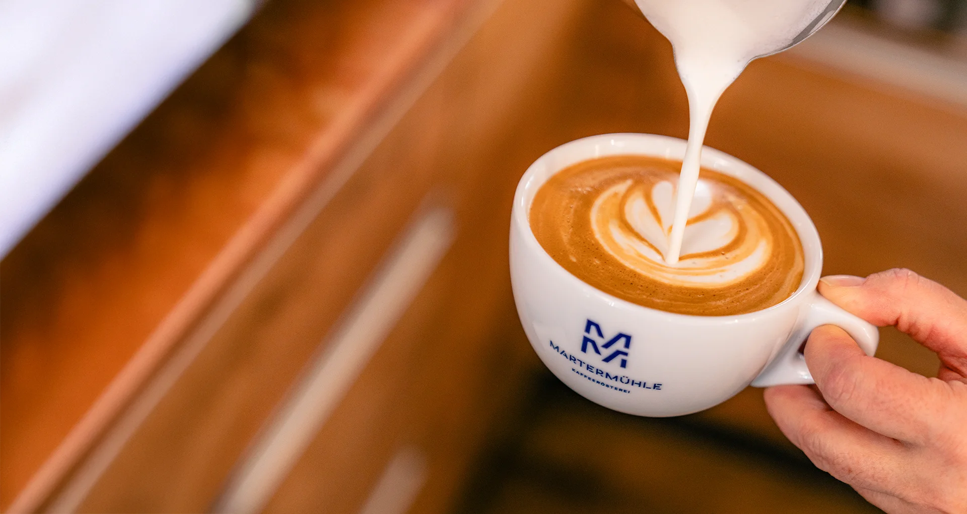 Martermühle-Mitarbeiterin, die eine Latte Art auf einen Cappuccino malt.