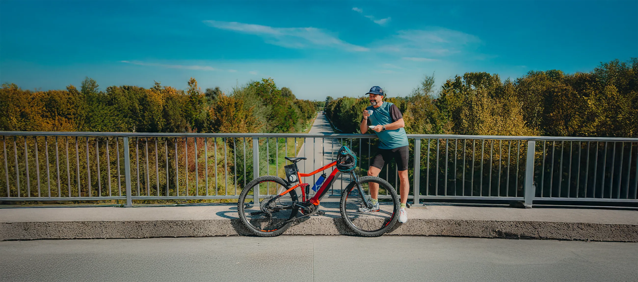 Fahrradfahrer an einer Brücke, der einen Bike Espresso trinkt.