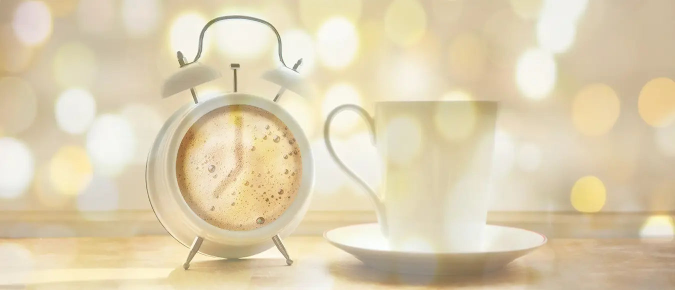 Ein Wecker und eine Tasse Kaffee der Kaffeerösterei Martermühle mit goldenem Bokeh