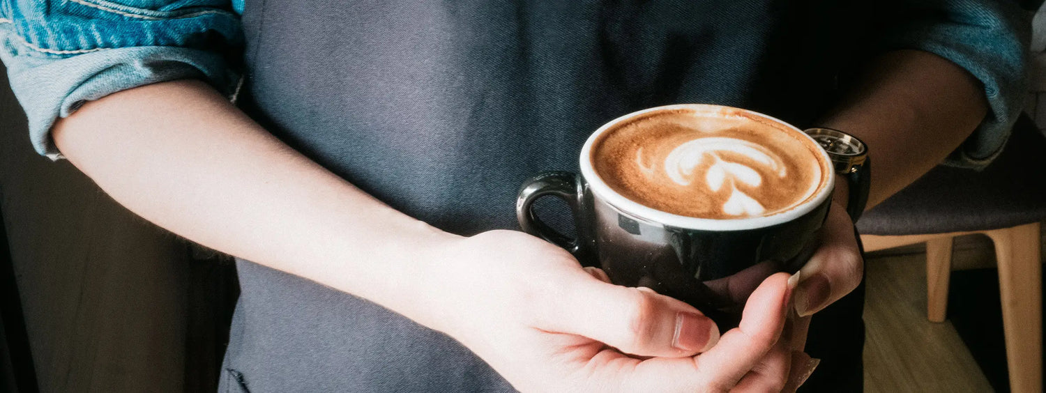 Ein Barista der Kaffeerösterei Martermühle mit einer Tasse Cappuccino mit Latte Art.