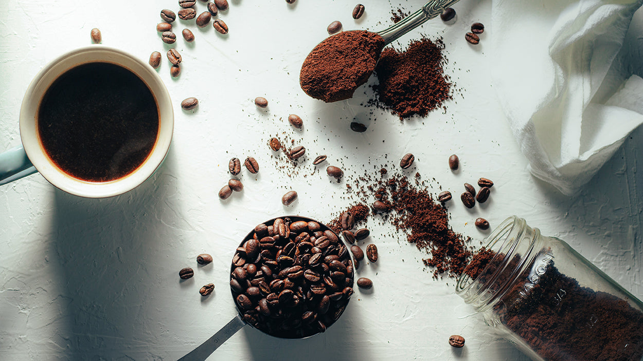 Top View einer Tasse Kaffee der Kaffeerösterei Martermühle, Kaffeebohnen und gemahlener Kaffee auf einem weißen Tisch