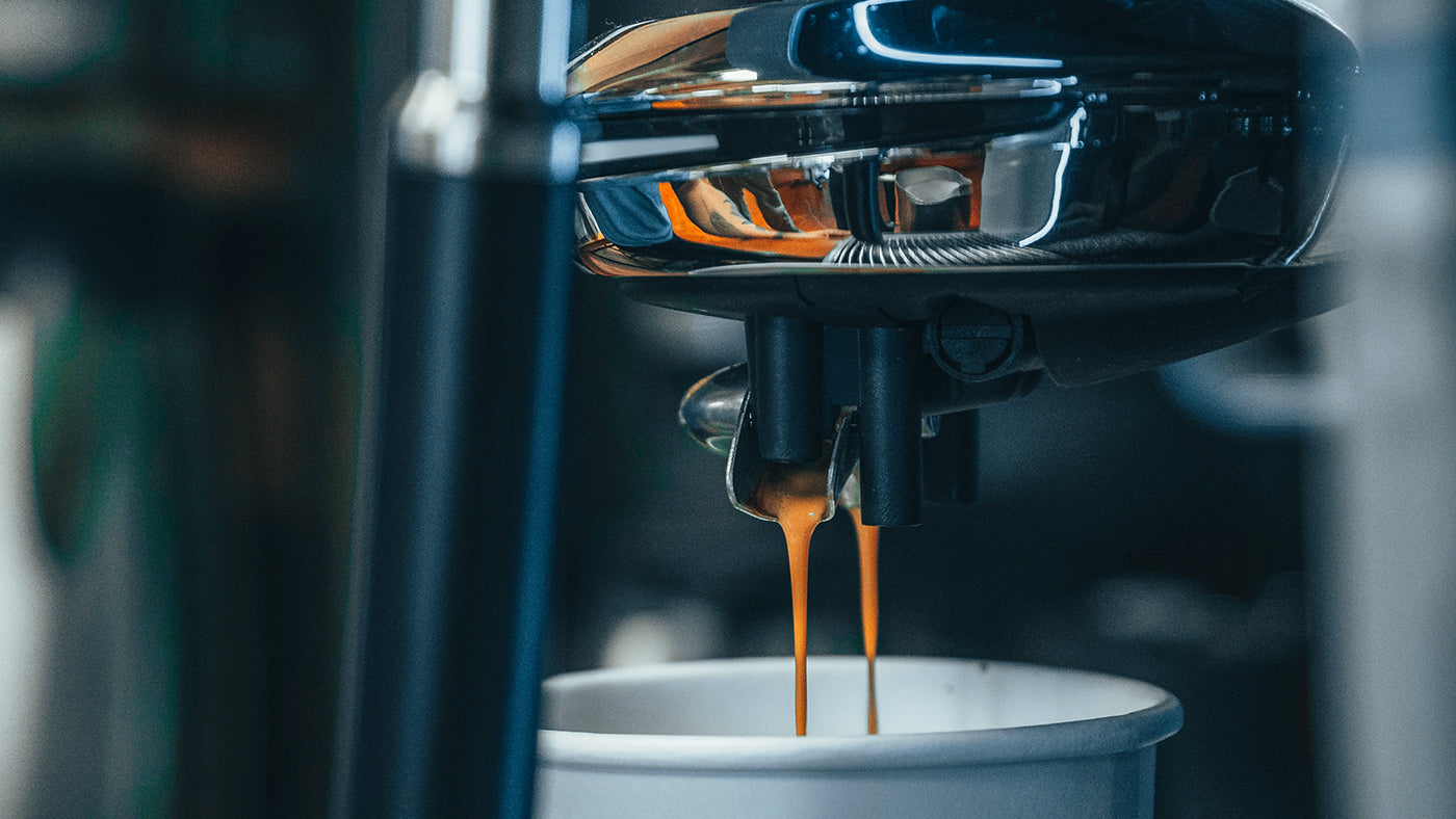 Frischer Espresso fließt aus den Düsen eines Kaffeevollautomaten in eine Cappuccino-Tasse der Kaffeerösterei Martermühle