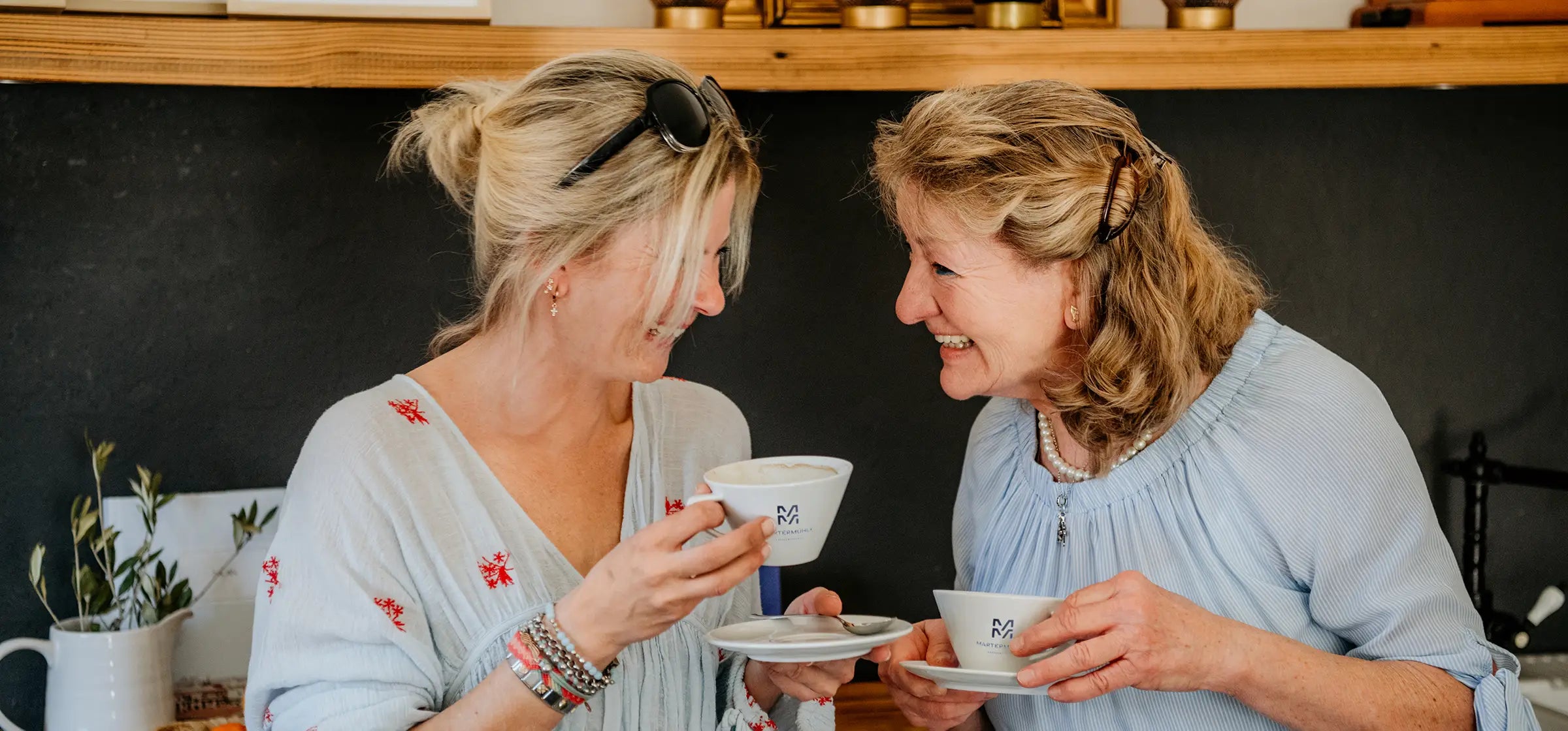 Zwei lachende Frauen beim Kaffee trinken mit Kaffeerösterei Martermühle Tassen.