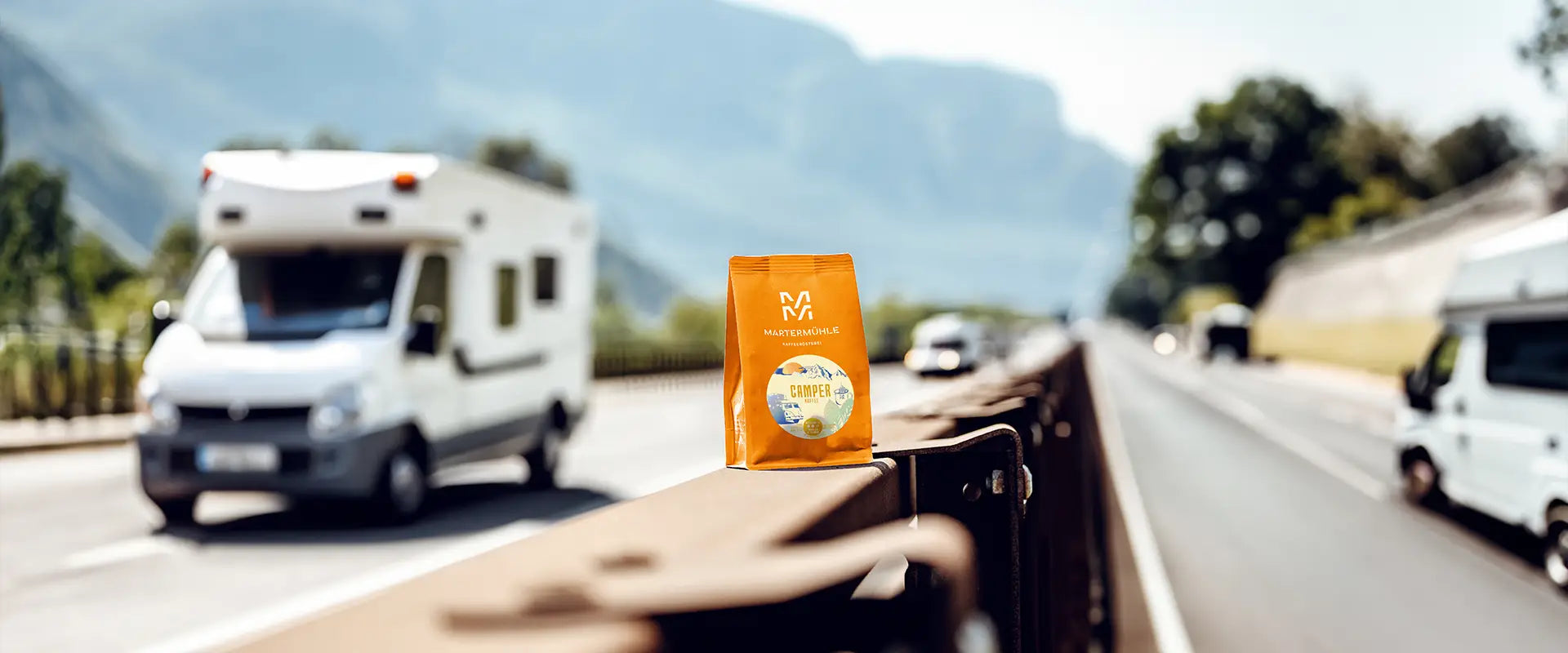 Eine orange Tüte Camper Espresso der Kaffeerösterei Martermühle auf der Leitplanke einer italienischen Autobahn.