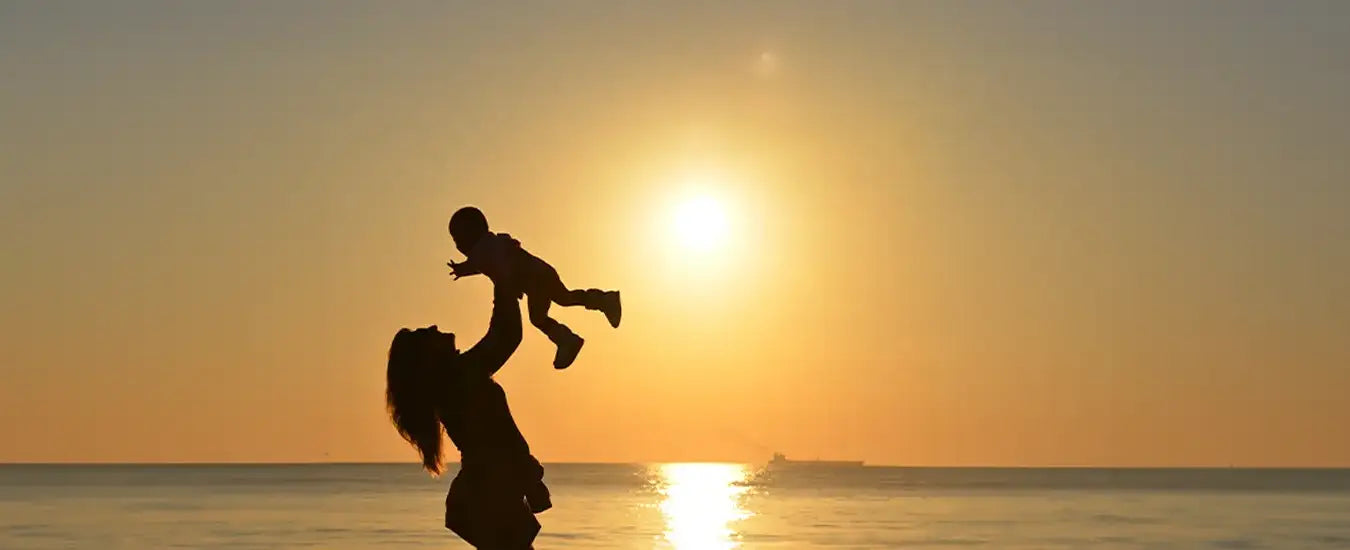 Eine Mutter die ihr Kind an einem Strand in die Luft wirft und wieder auffängt.