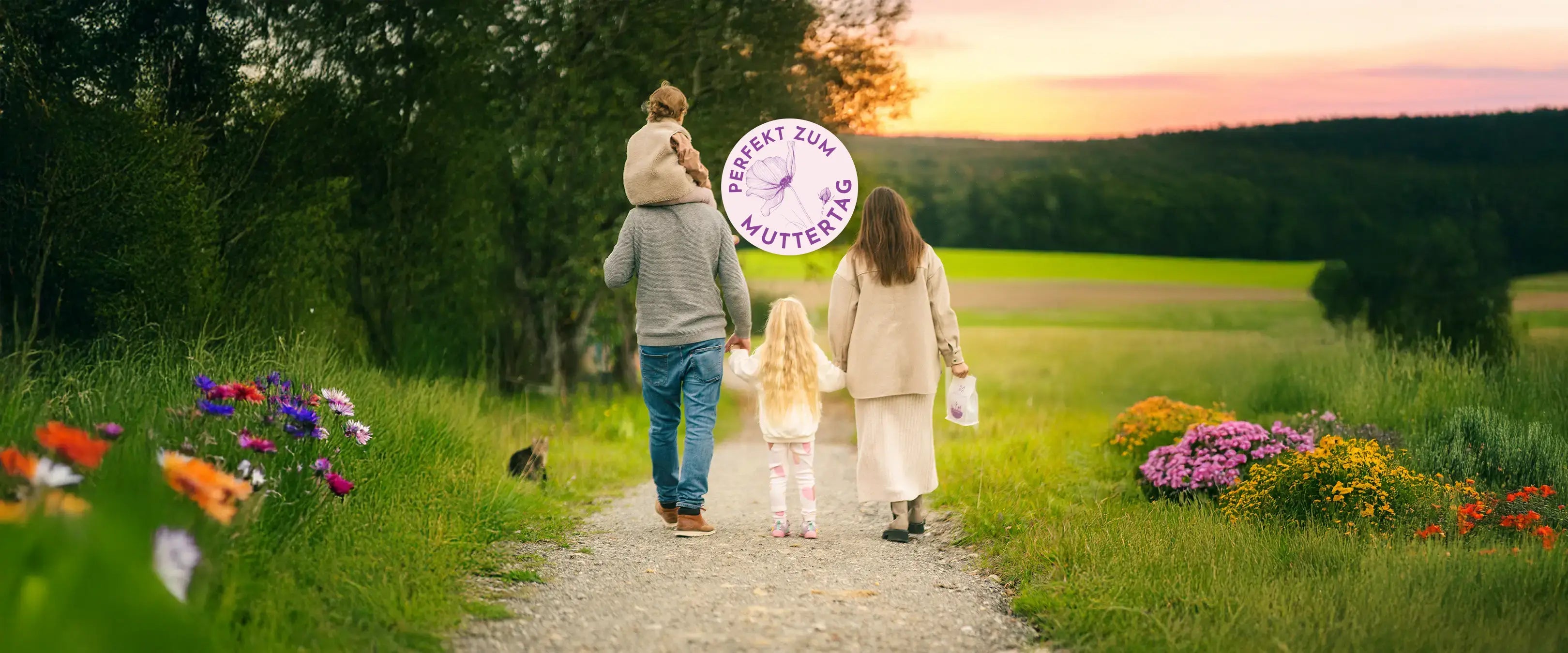 Familie auf einem Feldweg im Frühling mit einer Packung Mama Kaffee